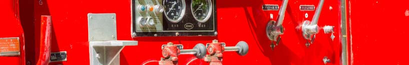 Closeup image of the side of a fire truck showing gauges and levers used in the vehicle control systems.